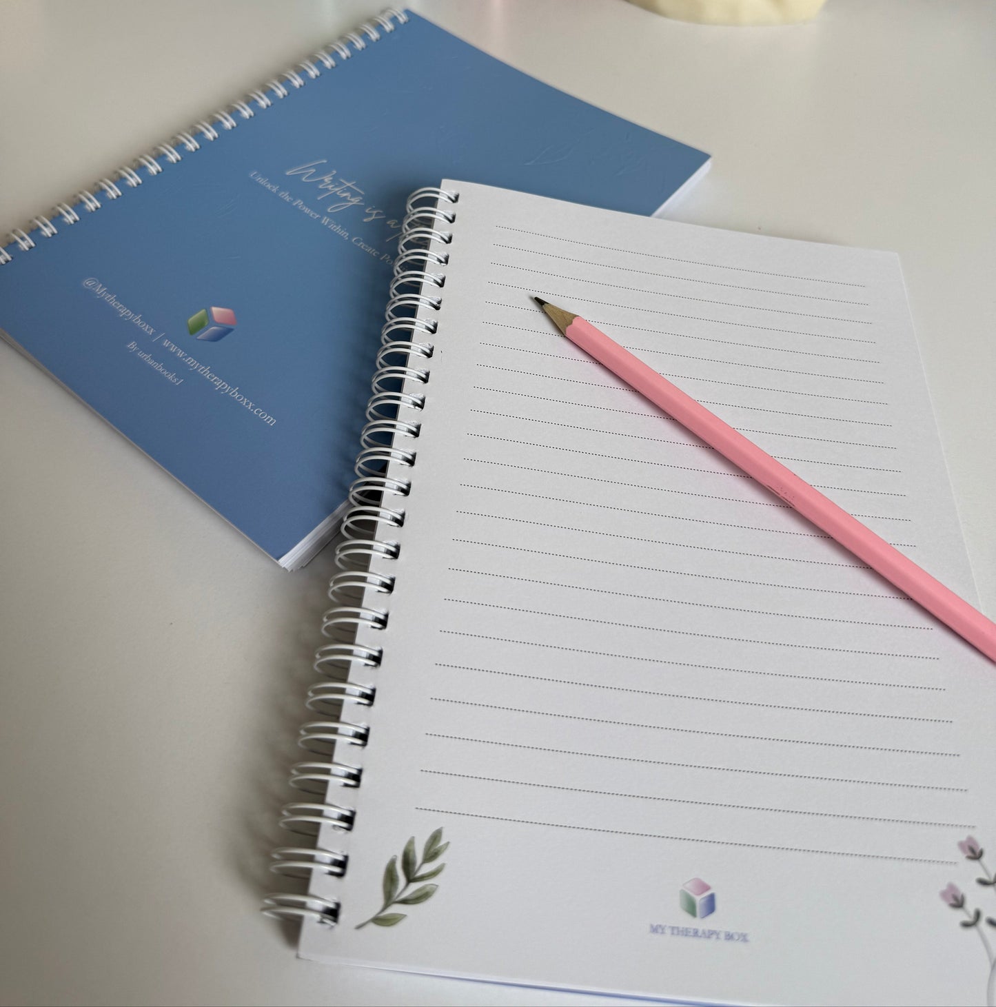 Notebook with a pink pencil on a desk next to stationery items