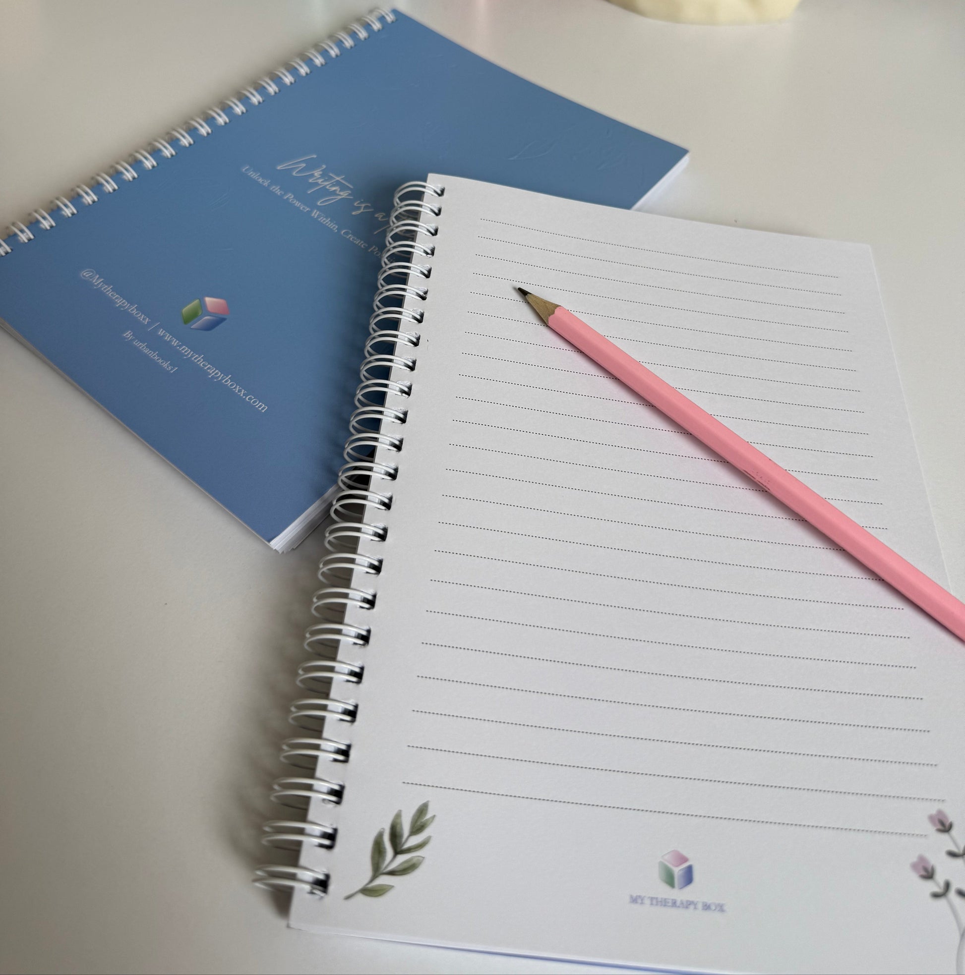 Notebook with a pink pencil on a desk next to stationery items